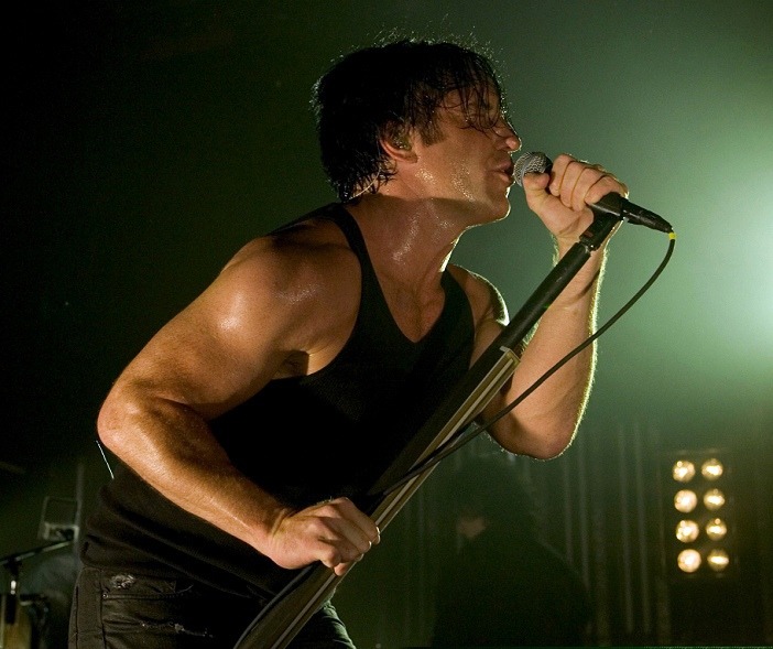 image of trent reznor wearing a tank top holding a microphone on the live: with teeth tour.