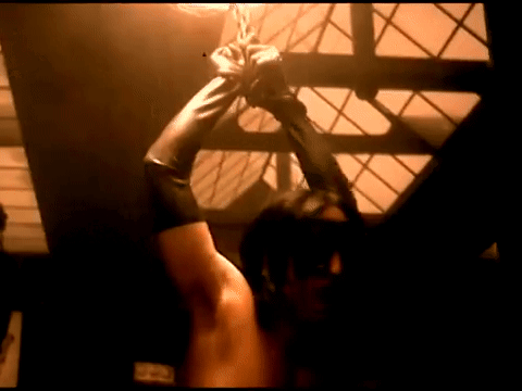 gif from the closer music video of trent reznor shirtless with his arms bound above his head, wearing leather gloves and a blindfold